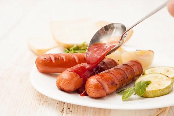 Grillwürste mit Ketchup auf weißem Hintergrund — Stockfoto