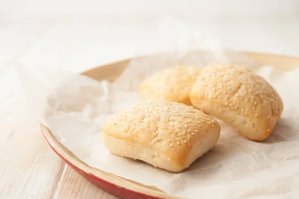 Cooked buns with sesame seeds on the baking paper — Stock Photo, Image