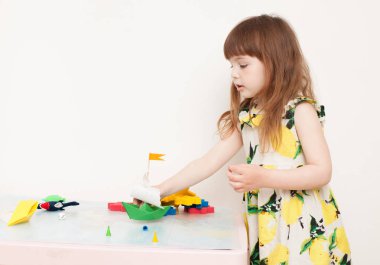 Kağıt tekne ile oynayan küçük bir kız