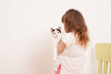 Beyaz bir kedi yavrusu ile oynayan bir çocuk
