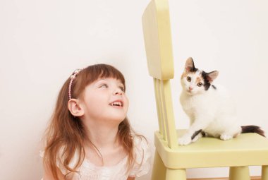 Beyaz bir kedi yavrusu ile oynayan bir çocuk