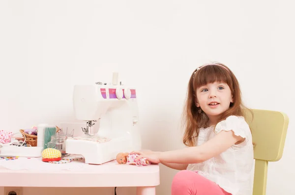 Meisje naait jurk poppen van stukjes weefsel — Stockfoto