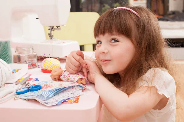 Girl sews dress dolls from pieces of fabric