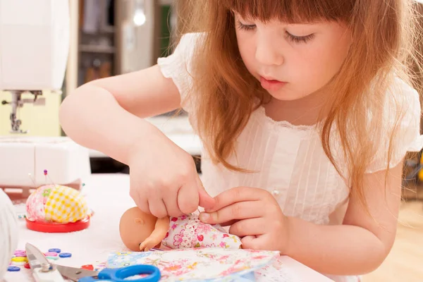 Meisje naait jurk poppen van stukjes weefsel — Stockfoto