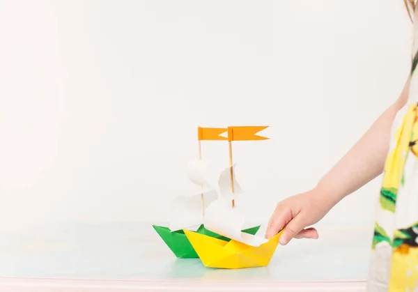 A little girl playing with paper boats