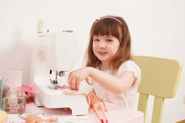 Meisje naait jurk poppen van stukjes weefsel — Stockfoto