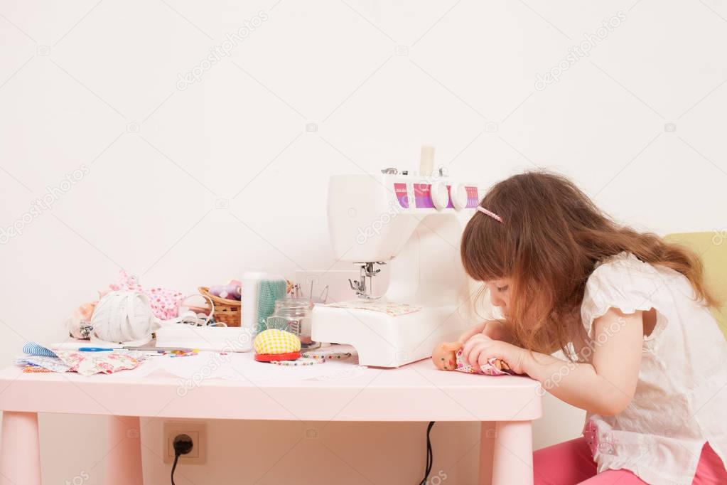 Girl sews dress dolls from pieces of fabric