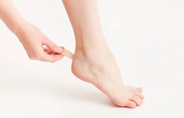 Sticking a patch on the foot of the foot on white — Stock Photo, Image