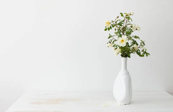 Садовые розы в белой вазе на столе — стоковое фото