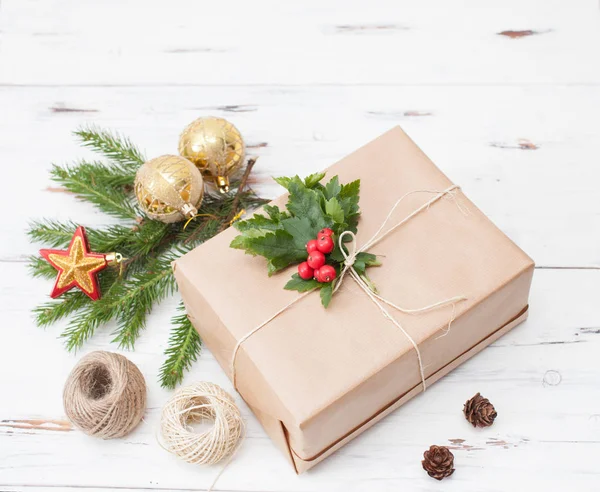 Zabalený dárek v obyčejný papír s vánoční větev a vánoční koule — Stock fotografie