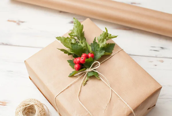 Zapakowany na prezent, dając w prosty papier z gałązka i czerwone jagody — Zdjęcie stockowe