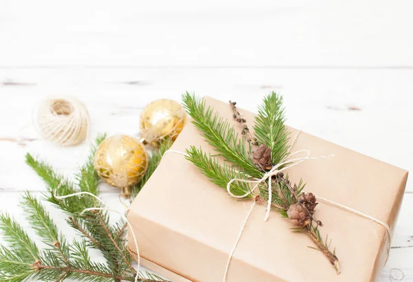 Zabalený dárek v obyčejný papír s vánoční větev a vánoční koule — Stock fotografie