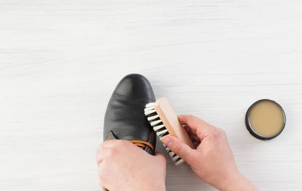 Mano masculina cepillada con crema zapatos negros en blanco — Foto de Stock