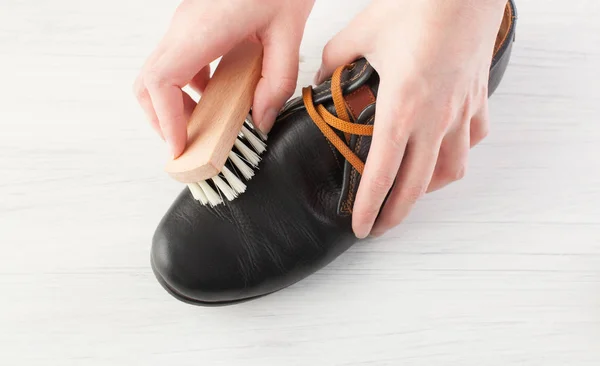 Las manos de las mujeres limpian los zapatos de cuero de los hombres en blanco — Foto de Stock