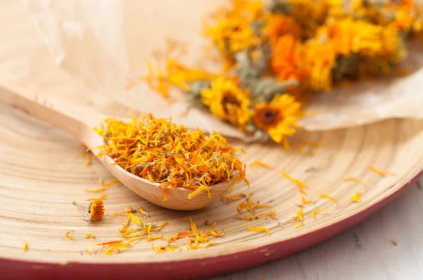 Las flores secas de caléndula en la cuchara de madera sobre la mesa —  Fotos de Stock