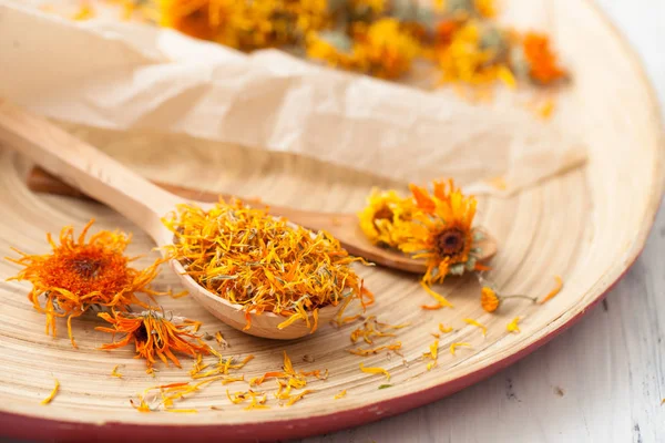 Las flores secas de caléndula en la cuchara de madera sobre la mesa —  Fotos de Stock