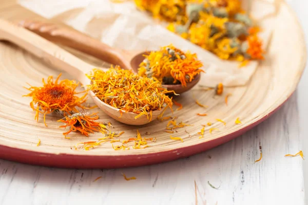 Droge calendula bloemen in een houten lepel op een tafel — Stockfoto