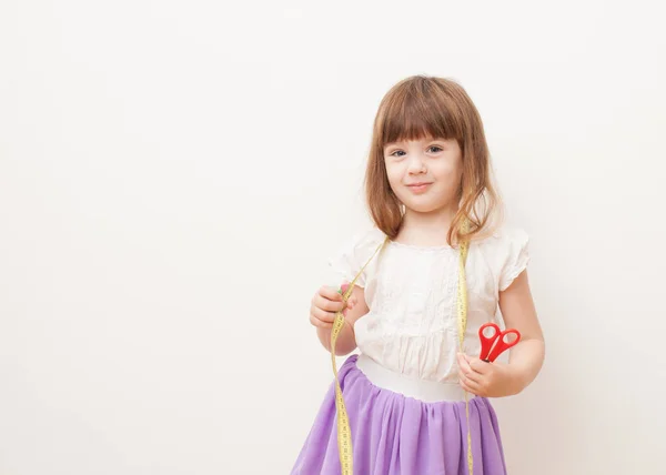 Meisje met de schaar, centimeter en naaigaren in handen — Stockfoto