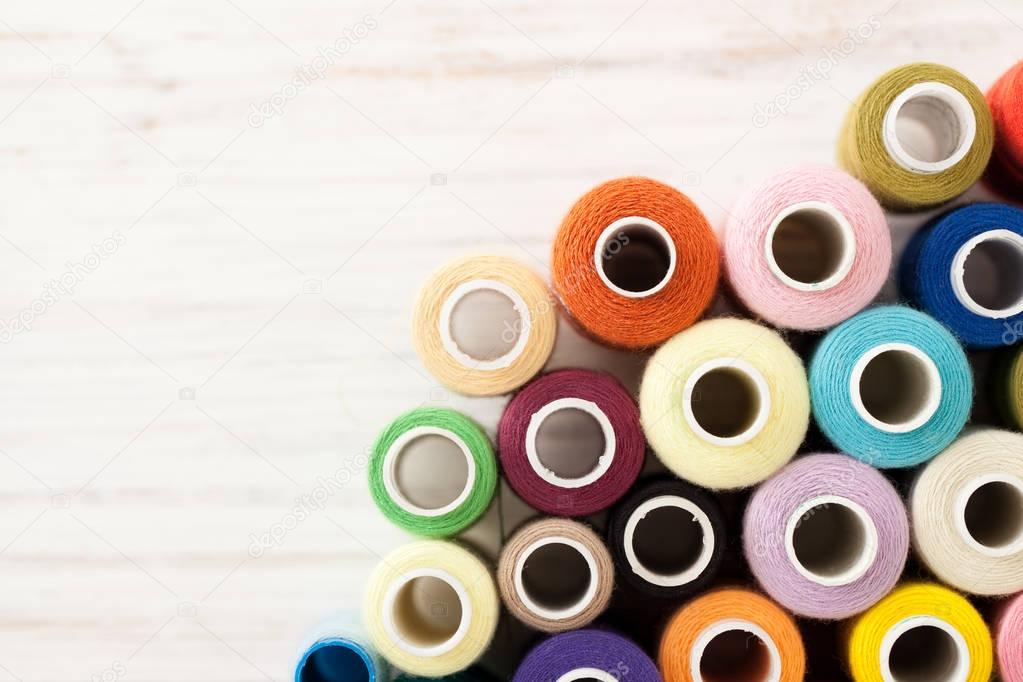 Background of colorful sewing threads on white table