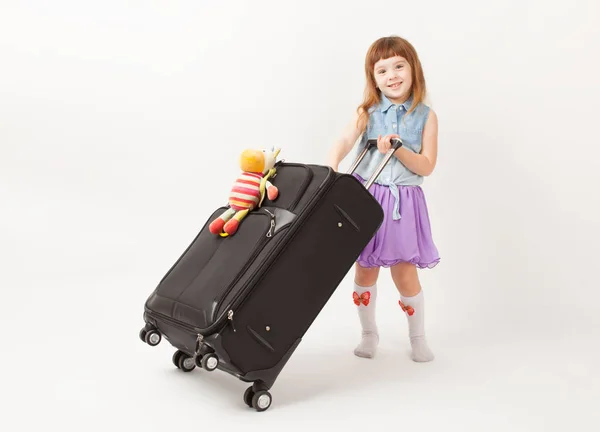 Girl standing with travel suitcase and smiling — Stock Photo, Image