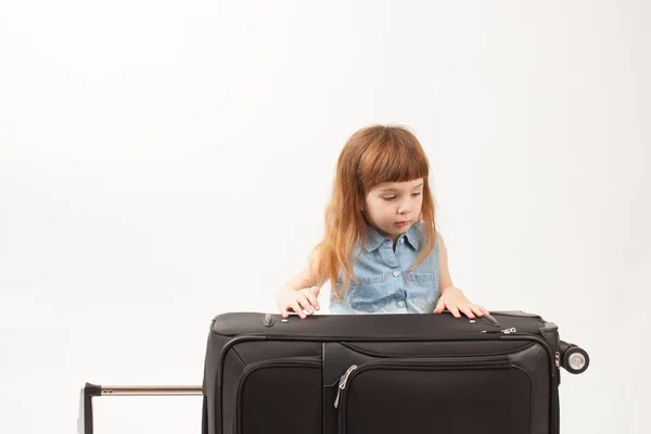 Το κορίτσι βλέπει μια βαλίτσα σε λευκό φόντο — Φωτογραφία Αρχείου