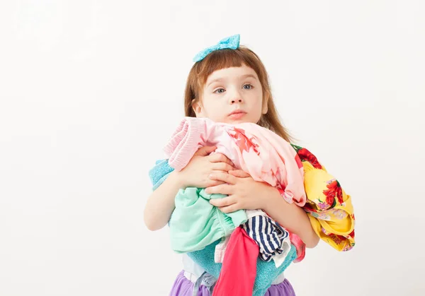 Doordachte meisje met een armful van kleren in zijn hand — Stockfoto