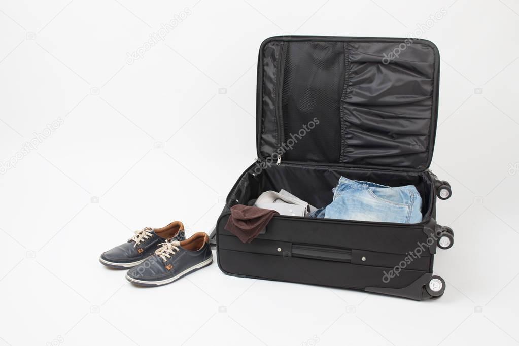 Mens shoes and outdoor suitcase with things on a white