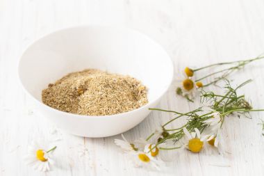 Beyaz bir tabloda bir kase kuru papatya çiçeği