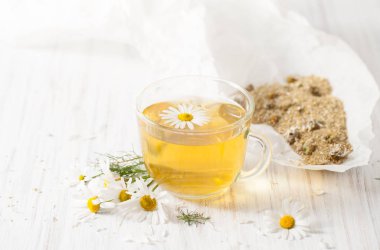 Beyaz bir masada bir fincan demlendi kuru papatya çiçeği