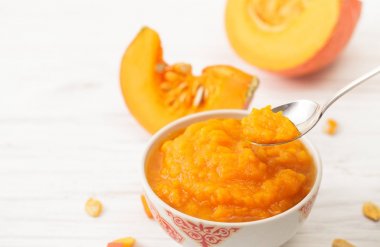 Kabak püresi bir kaşık ve balkabağı beyaz masaya kesilmiş