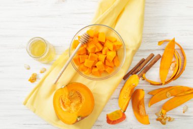 Beyaz bir masada bir kase ve bal parça parça oyulmuş kabak