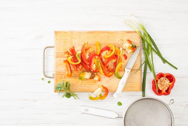 Hackad flerfärgad paprika, grön lök och basilika på köket styrelse — Stockfoto