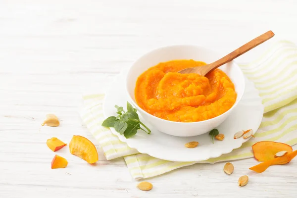 Pumpkin puree in a plate of pumpkin slices on a white table — Stock Photo, Image