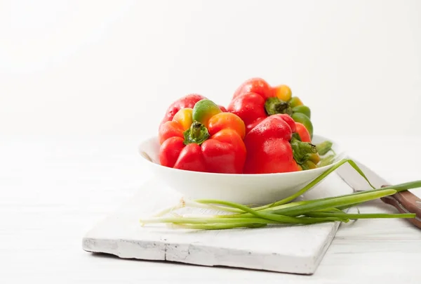 Sweet colorful raw peppers, green onions in white bowl — Stock Image Sweet colorful raw peppers, green onions in white bowl Stock Photo