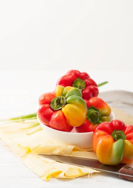 Sweet colorful raw peppers, green onions on a white table — Stock Image Sweet colorful raw peppers, green onions on a white table Royalty Free Stock Photos