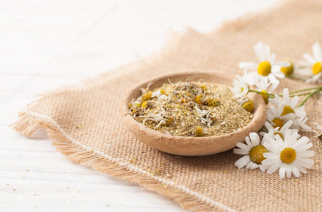 Dry chamomile flowers in a clay bowl