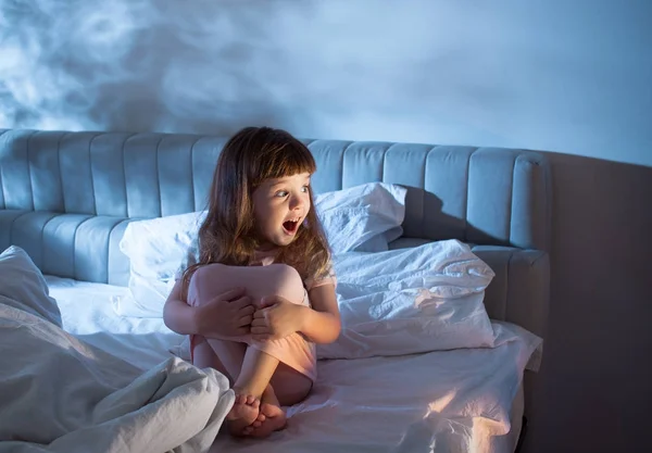 A menina grita enquanto está sentada na cama durante a noite — Fotografia de Stock
