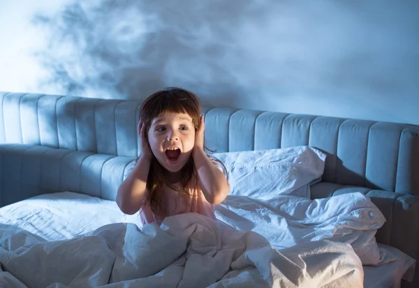 Девушка на кровати кричала, закрывая его уши руками. — стоковое фото