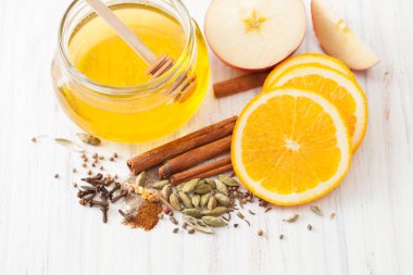 Beyaz ahşap masa bal, tarçın, karanfil ve portakal dilimleri