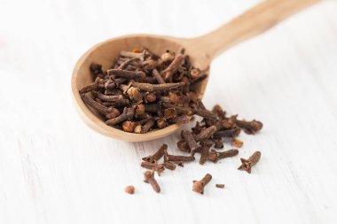 Beyaz ahşap masa üstünde tahta kaşık karanfil