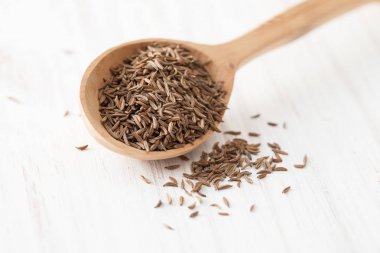 Tahta kaşık Beyaz ahşap masa üzerinde siyah kimyon