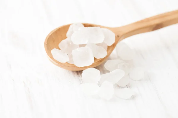 Zucchero grumo in cucchiaio di legno sul tavolo di legno bianco — Foto Stock