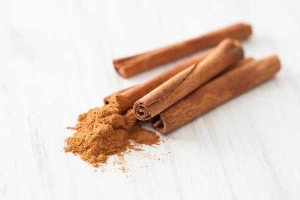 Varas de canela e canela moída em uma mesa de madeira branca — Fotografia de Stock