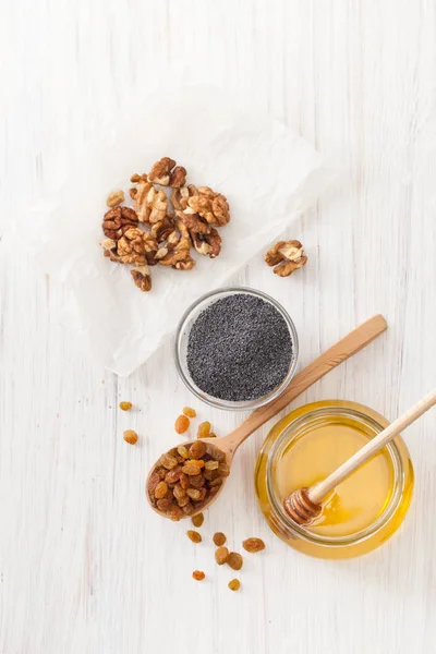 Nötter, honung, russin och vallmofrön på vit — Stockfoto