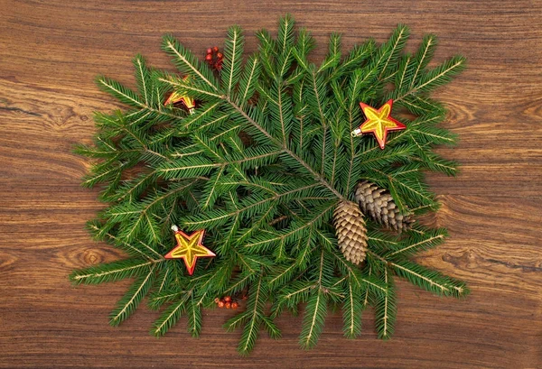 Ramas de árbol de Navidad con estrellas y conos de pino sobre fondo de madera marrón — Foto de Stock