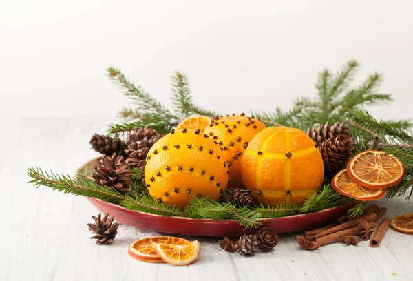 Oranges décorées avec clous de girofle sur branches d'épinette avec cônes — Photo