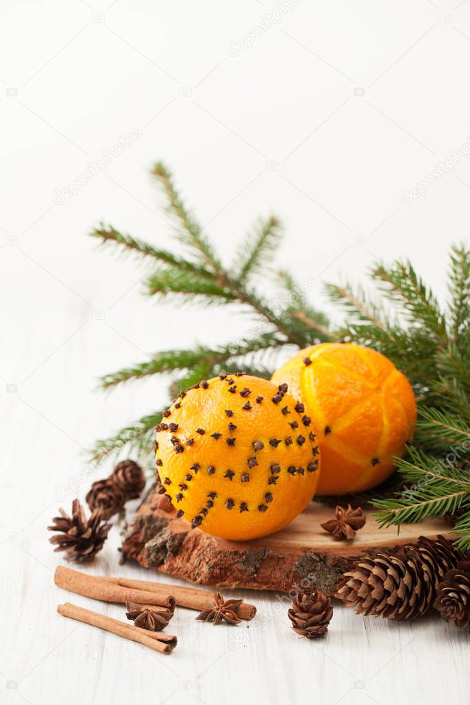 Two oranges decorated with cloves, cinnamon and fir branch