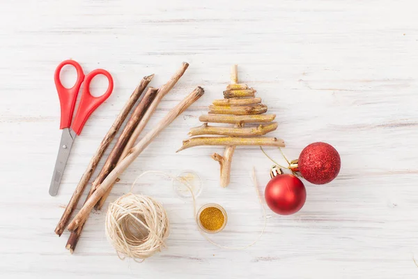 Ein hausgemachter Weihnachtsbaum aus Zweigen mit roten Kugeln auf weißem Grund — Stockfoto