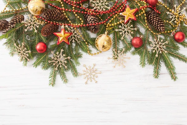 Rami di abete rosso con ornamenti natalizi su sfondo bianco in legno — Foto Stock