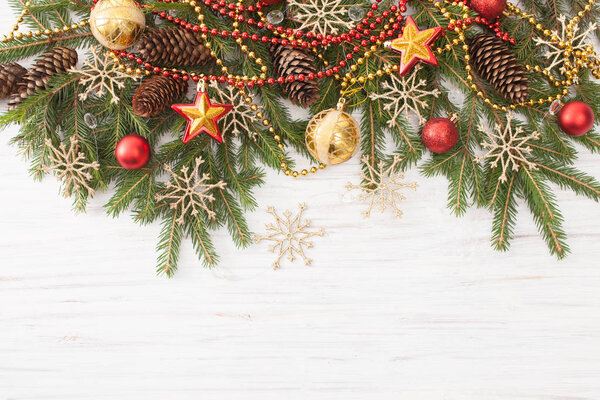 Spruce branches with Christmas ornaments on white wooden background